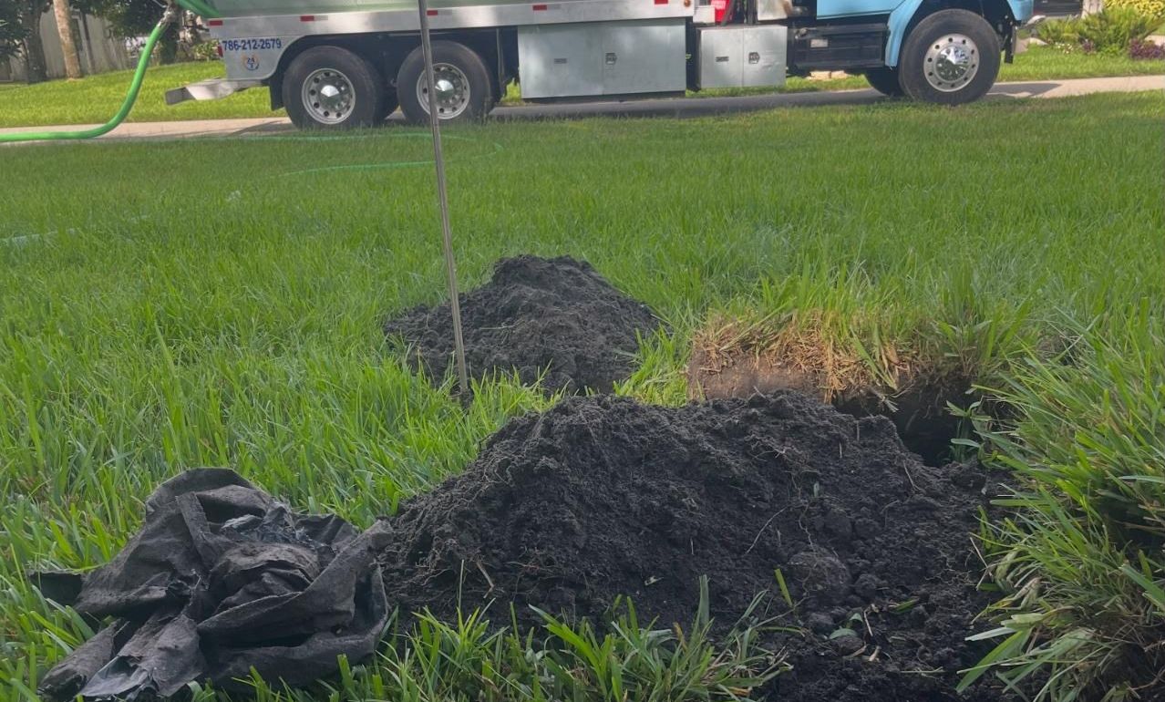 Probe rod in the lawn while checking a drain field, vacuum truck parked on the street